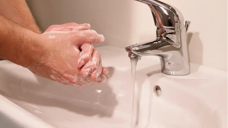 person vasker hænder med sæbe og rindende vand fra vandhane